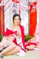 A woman in a kimono sitting on the ground next to another woman.