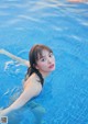 A woman in a blue swimsuit floating in a pool.