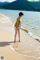 A woman standing on a beach next to the ocean.