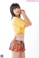 A woman in a yellow shirt and a colorful skirt.