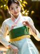 A woman in a green and white hanbok poses for a picture.