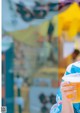 A woman holding a cup of orange juice in her hand.
