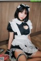 A woman dressed as a maid sitting on the floor.