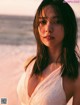 A woman in a white dress standing on a beach.