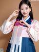 A woman in a pink and blue hanbok poses for a picture.